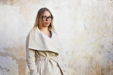 Street portrait of a blonde with long hair, in a light beige raincoat