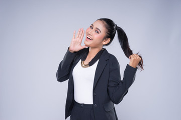 An attractive woman wearing business attire with gestures towards copyspace area isolated on grey. Good for manipulation works for technology, transportation, business or finance theme.