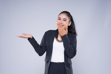 An attractive woman wearing business attire with gestures towards copyspace area isolated on grey. Good for manipulation works for technology, transportation, business or finance theme.