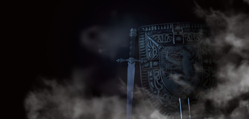 photo of shield knight armor and sword in the fog smoke over dark background. Medieval period...