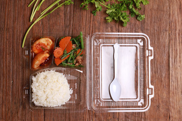 Thai package lunch to go on wood table.composition (top view).