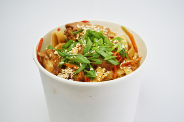 Thai noodles with chicken and vegetables in a bowl for delivery on a white background
