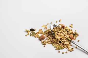 A spoon with granola sprinkled over a white background. Close photo. Green buckwheat with nuts and coconut. Healthy food concept.