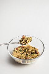 Green buckwheat granolo with nuts and coconut in a bowl on a white background close up. Healthy eating concept.