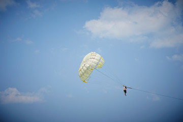 Woman enjoying parasailing, sky background 