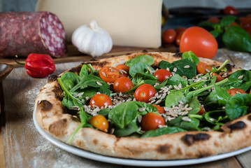 Italian style pizza, fresh arugula and cherry tomatoes prepared on wooden boards