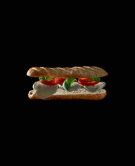 schwebende Zutaten eines leckeren Veggie Sandwiches auf schwarzem Hintergrund