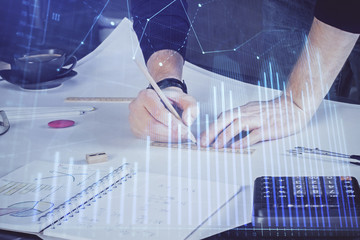Double exposure of man writing on paper with forex graph.
