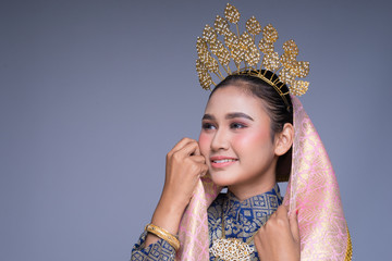 Headshot portrait of a beautiful Malaysian traditional female dancer in traditional dance outfit with a charming smile. Isolated on grey.