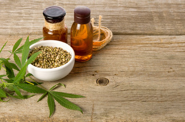 Hemp oil. Two brown glass vials, cannabis green leaves and grains stand on a wooden old vintage table background