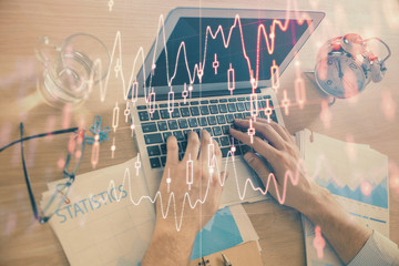 Multi exposure of forex graph with man working on computer on background. Concept of market...