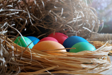 Multi-colored Easter eggs lie in a straw.