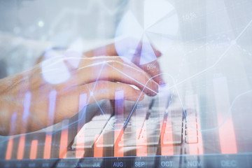 Multi exposure of graph with man typing on computer in office on background. Concept of hard work. Closeup.