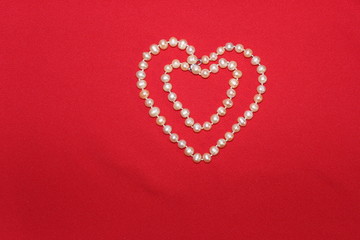 Heart made of pearls on a red background. Heart made of beads. Heart for valentines day.