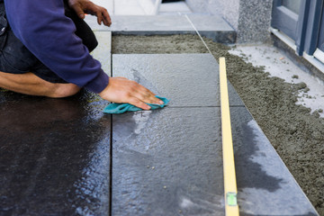 The worker puts stone slabs as the entrance stairs to the house