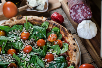 Italian style pizza, fresh arugula and cherry tomatoes prepared on wooden boards
