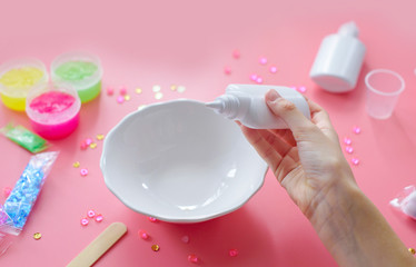 a girl making slime herself. child making slime on pink background.