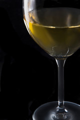 A glass of white wine on black background