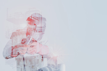 Double exposure of a downtown city and industrial worker welder is welding steel structure with...