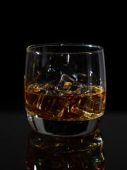 Whiskey splash in glass with ice on a dark background