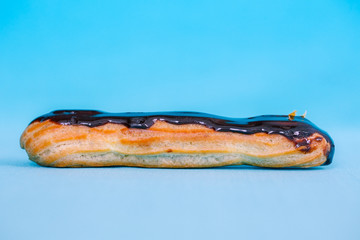Eclair with chocolate on a blue background