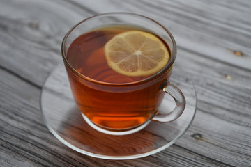 A cup of black tea with lemon on a wooden table
