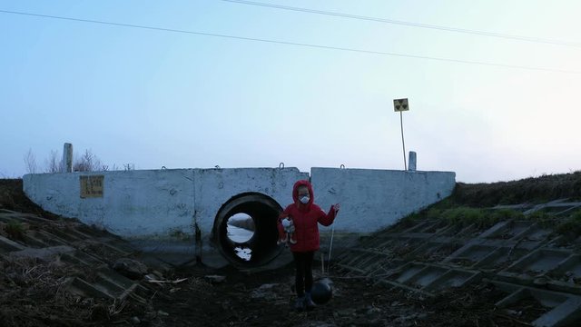 Ditch child in a respirator red jacket with a toy and a black ball, fear and apocarypse, radiation hopelessness
