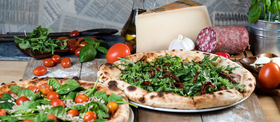 Fototapeta premium Italian style pizza, fresh arugula and cherry tomatoes prepared on wooden boards