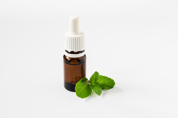 isolated glass bottle with aromatic oil and a sprig of mint on a white background