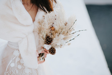 Mariée dans le froid tenant son bouquet de fleurs séchées