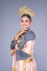 A beautiful Malaysian traditional female dancer with a charming smile performing a cultural dance steps in a traditional outfit. Half length isolated in grey.