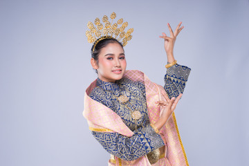 A beautiful Malaysian traditional female dancer with a charming smile performing a cultural dance steps in a traditional outfit. Half length isolated in grey.