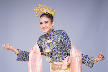 A beautiful Malaysian traditional female dancer with a charming smile performing a cultural dance steps in a traditional outfit. Half length isolated in grey.