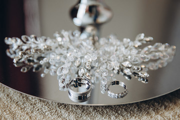 wedding rings and jewelry of the bride lie on a silver tray