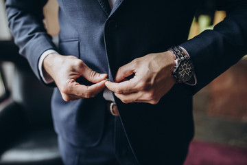 man in white shirt with a watches on his hand puts on formal suit