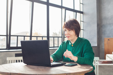 Real people. Mature woman working laptop computer indoors