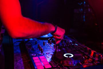 hands of a DJ mixing music on a professional controller in a booth