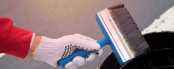 Worker applies bitumen mastic on the foundation