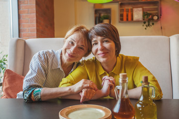 Happy mature women eating and chatting in restaurant