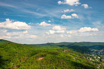 Obraz premium Landscape of green forest on the hills in summer with blue sky and white clouds. Photo taken in West Germany.