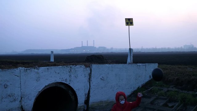  Waste ditch child in a respirator red jacket with a toy and a black ball, from the back of the factory, radiation reactor fear and apocarypse, hopelessness