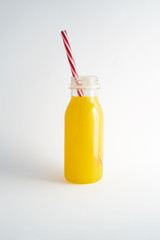 Bottle of orange juice with red straw on white background