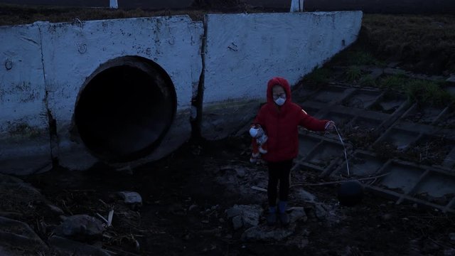 Waste ditch child in a respirator red jacket with a toy and a black ball, from the back of the factory, radiation reactor fear and apocarypse, hopelessness