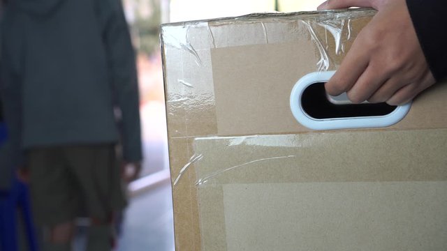 Hand Parcel delivery man holding delivering package box to homeowner / deliver office. Close up of delivery postman carry big cardboard to owner, Delivery shipment order e-commerce service to customer