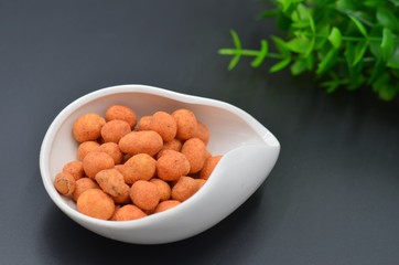 Shrimp flavored peanuts on a white plate on a black background