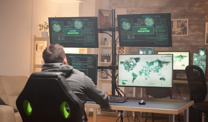 Rear view of cyber criminal hacking people database