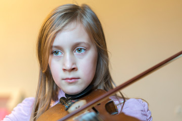 little girl playing the violin at home. Child or little girl playing violin indoors at home. copy...