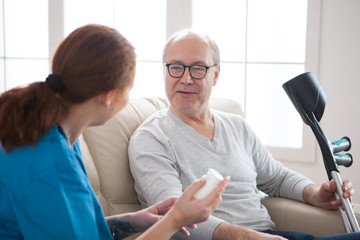 Smiling senior man with crutches in nursing home