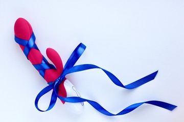 Sex toy for adult, design pink vibrator with a blue gift ribbon isolated on light background....