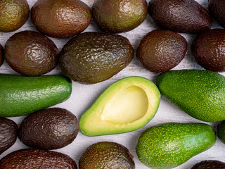 Mix of ripped and green avocados on white wooden board
